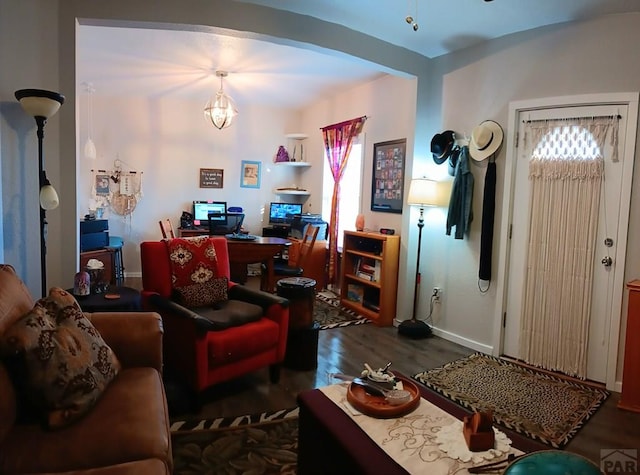 living area with plenty of natural light, baseboards, arched walkways, and dark wood-type flooring