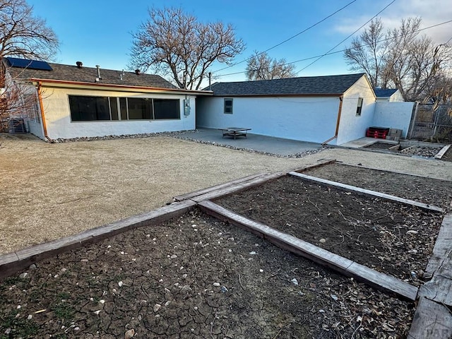 back of house with a patio area, a garden, fence, and stucco siding