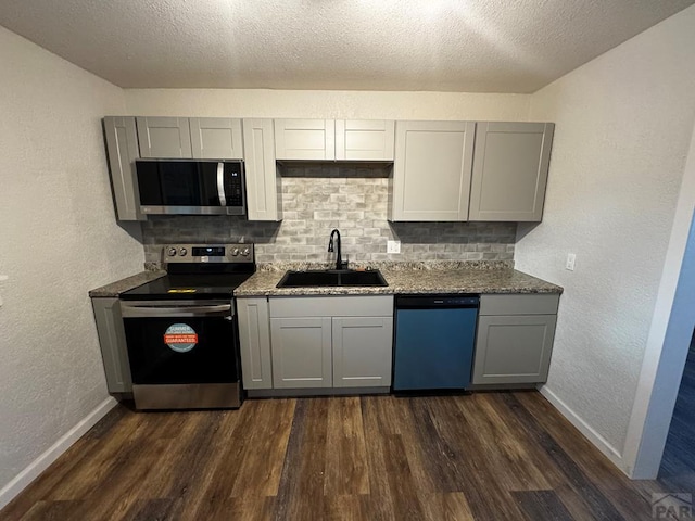 kitchen featuring stainless steel appliances, a sink, and gray cabinetry