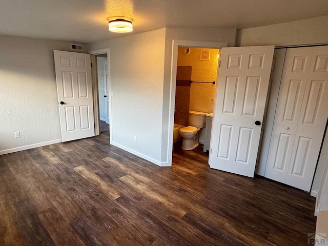 unfurnished bedroom featuring dark wood-type flooring, a closet, visible vents, and baseboards