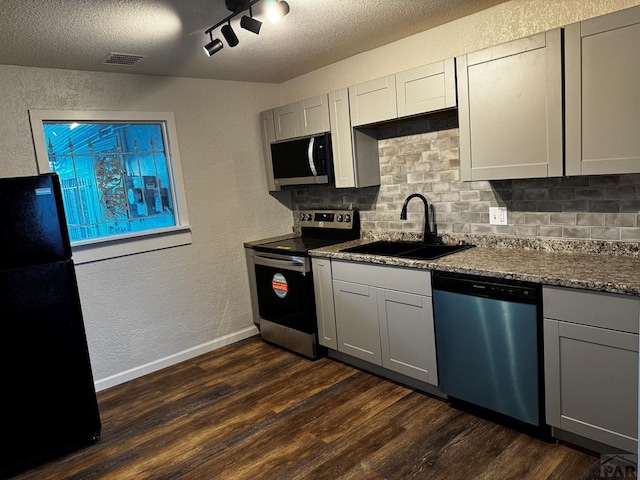 kitchen with dark wood finished floors, visible vents, a textured wall, appliances with stainless steel finishes, and a sink