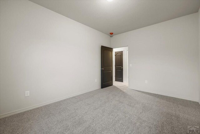 spare room featuring carpet and baseboards