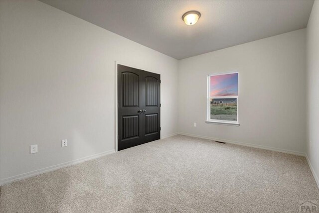 unfurnished room with carpet floors, visible vents, and baseboards