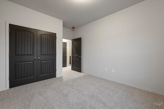 unfurnished bedroom featuring carpet, baseboards, and a closet