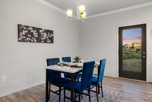 dining space with baseboards, a chandelier, crown molding, and wood finished floors