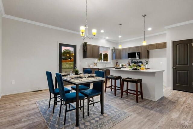 dining room featuring light wood finished floors, baseboards, and crown molding