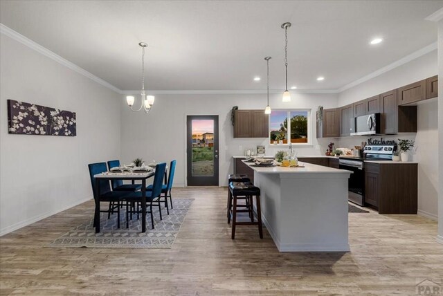 kitchen with appliances with stainless steel finishes, light countertops, a kitchen island, and hanging light fixtures