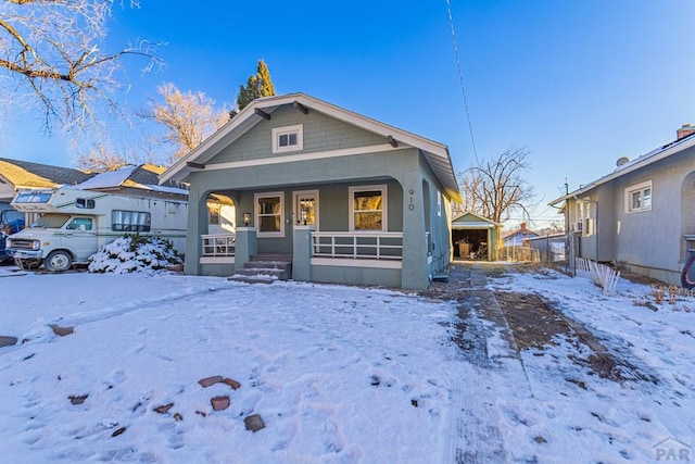 view of front facade with a garage, covered porch, and stucco siding