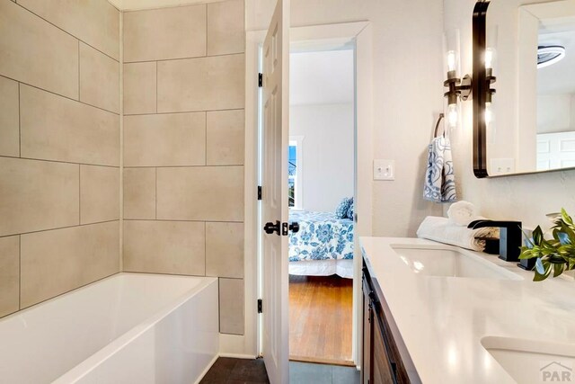 ensuite bathroom with a tub, a sink, ensuite bath, and double vanity