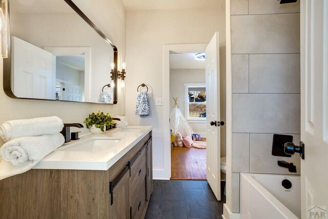 full bathroom with wood finished floors, a sink, toilet, and double vanity