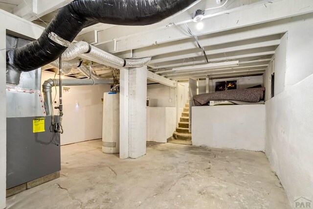 unfinished basement featuring stairway, gas water heater, and heating unit