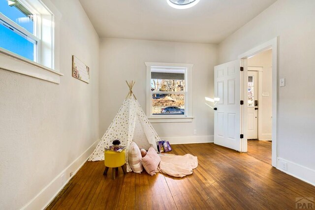 game room with baseboards and dark wood finished floors