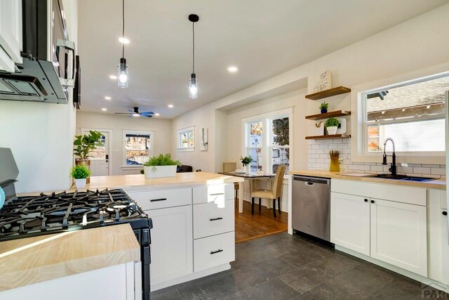 kitchen with decorative light fixtures, stainless steel dishwasher, white cabinetry, black range with gas cooktop, and a sink