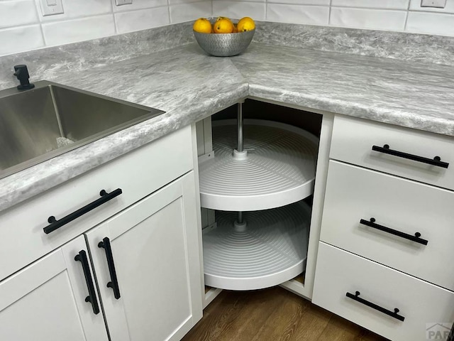 interior details with dark wood-style floors, light countertops, a sink, and white cabinets