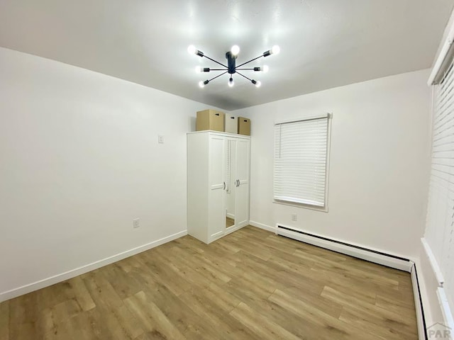 unfurnished bedroom with light wood-type flooring, a baseboard radiator, and baseboards