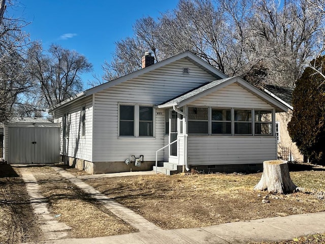 bungalow-style home with entry steps, an outbuilding, concrete driveway, crawl space, and a shed