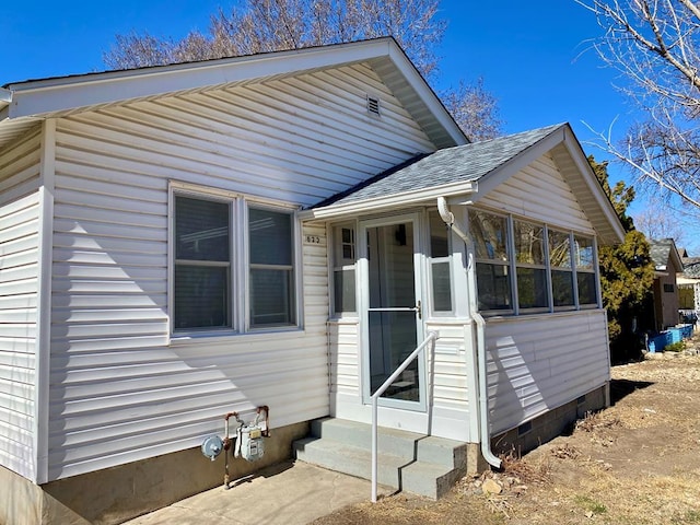 view of front of property featuring entry steps, a shingled roof, crawl space, and a sunroom