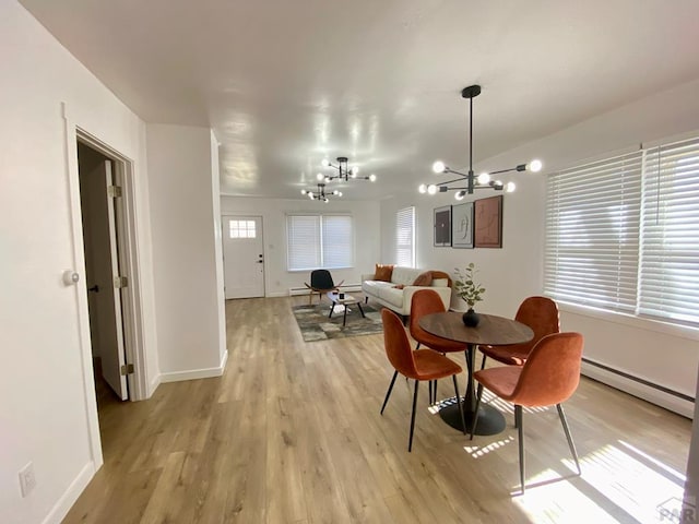 dining area featuring light wood finished floors, baseboards, a baseboard heating unit, and a notable chandelier