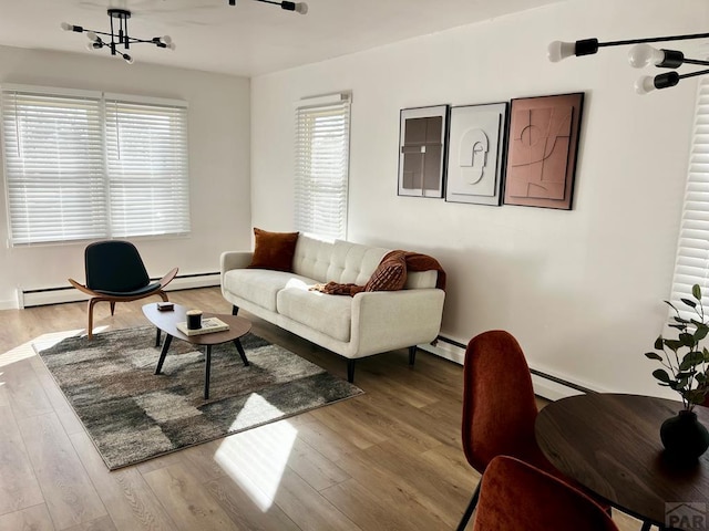 living room with a notable chandelier, baseboard heating, and wood finished floors