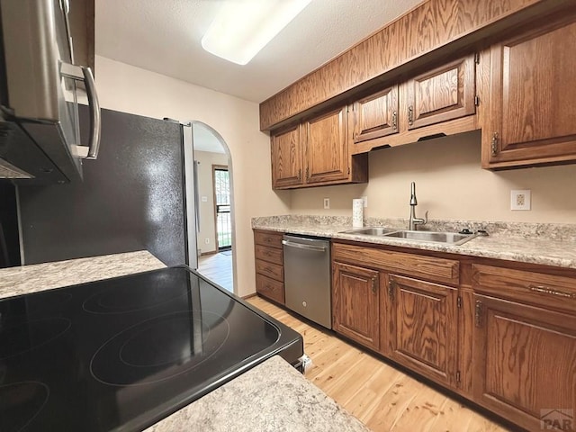 2302 Cartier Dr Unit A, Pueblo, CO 81005 - kitchen with stainless steel appliances, light wood finished floors, arched walkways, light countertops, and brown cabinetry