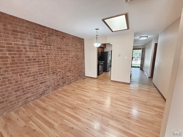 2302 Cartier Dr Unit A, Pueblo, CO 81005 - unfurnished dining area featuring brick wall and light wood finished floors