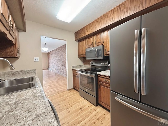 2302 Cartier Dr Unit A, Pueblo, CO 81005 - kitchen featuring appliances with stainless steel finishes, light wood-type flooring, light countertops, brick wall, and brown cabinets