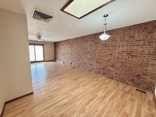 2302 Cartier Dr Unit A, Pueblo, CO 81005 - unfurnished living room with brick wall, light wood-style floors, and a ceiling fan