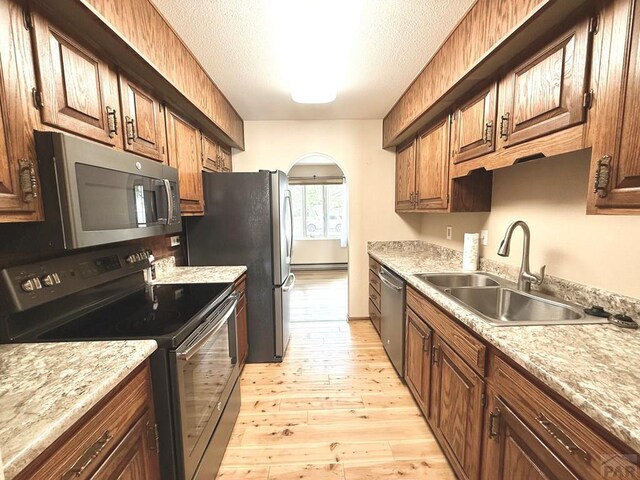 2302 Cartier Dr Unit A, Pueblo, CO 81005 - kitchen with stainless steel appliances, light wood-style flooring, light countertops, arched walkways, and a textured ceiling