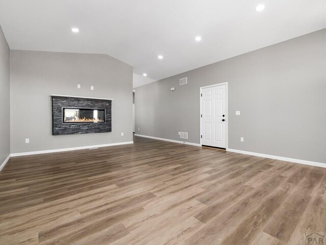 unfurnished living room featuring lofted ceiling, wood finished floors, visible vents, and baseboards