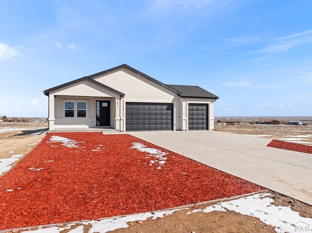 view of front of house featuring concrete driveway, an attached garage, and stucco siding