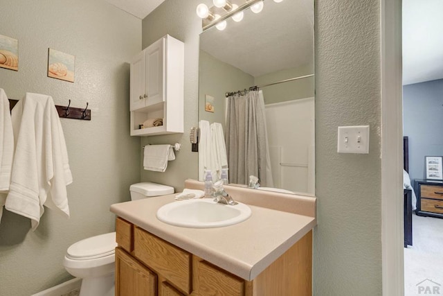 full bath with vanity, a textured wall, and toilet
