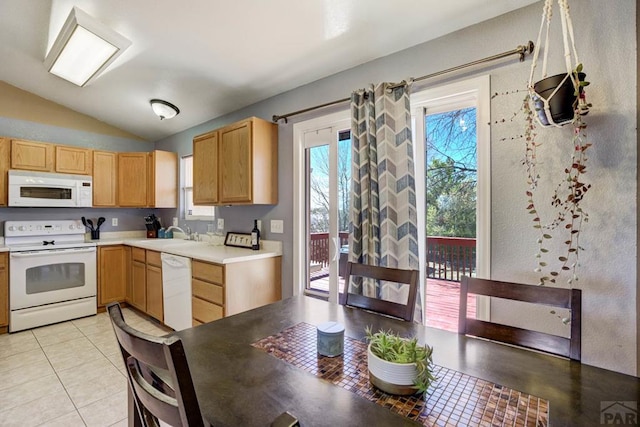 kitchen featuring lofted ceiling, light brown cabinetry, white appliances, light countertops, and a sink