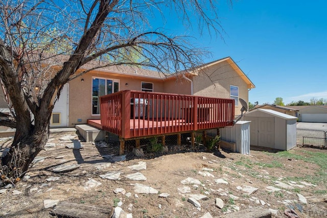 back of house featuring a storage shed, a wooden deck, an outdoor structure, and stucco siding