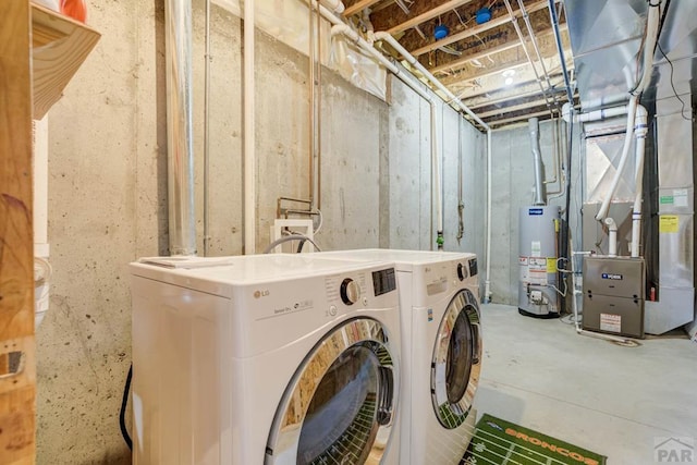 washroom with water heater, heating unit, laundry area, and washer and dryer