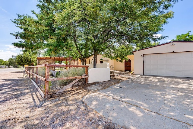 view of front of property featuring concrete driveway, a fenced front yard, and stucco siding