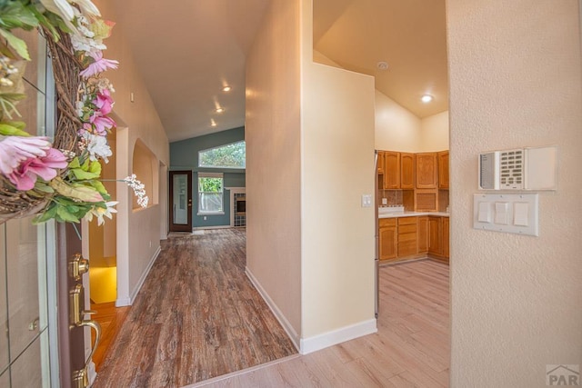 hall with light wood-style floors, recessed lighting, high vaulted ceiling, and baseboards