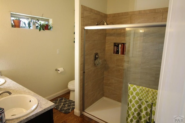 1470 Villa Spanada, Pueblo, CO 81006 - full bathroom featuring double vanity, a stall shower, toilet, and wood finished floors