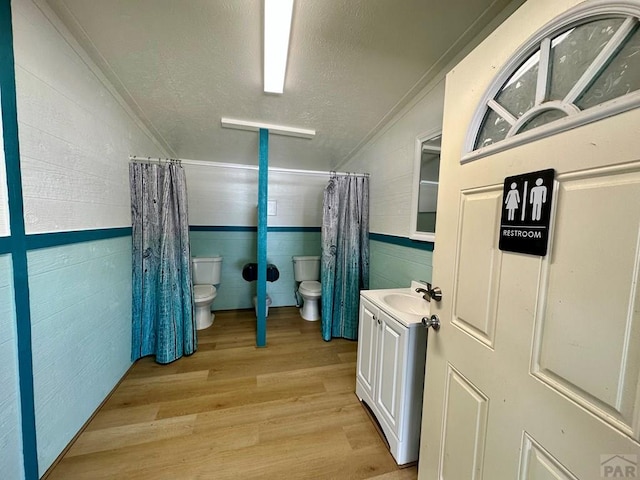 full bathroom with a shower with shower curtain, toilet, a textured ceiling, vanity, and wood finished floors