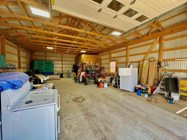 garage featuring metal wall, washer / clothes dryer, and freestanding refrigerator