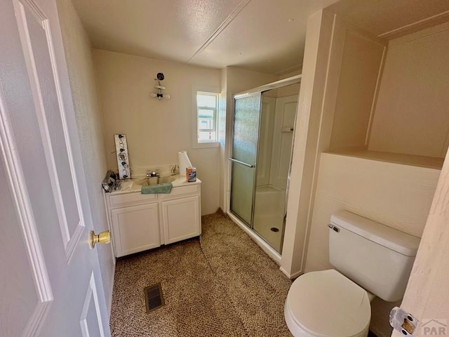 bathroom with toilet, a stall shower, visible vents, and a sink