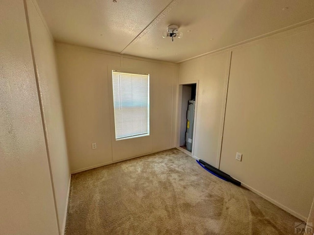 empty room featuring light colored carpet and water heater