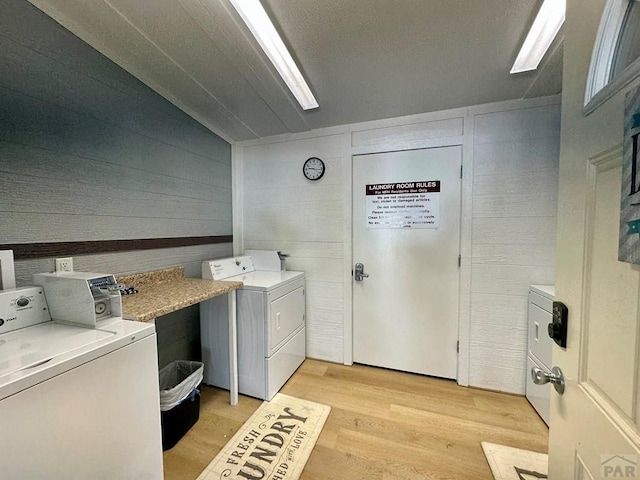 clothes washing area with light wood-type flooring and washing machine and dryer