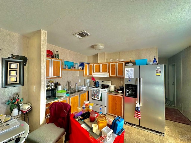 kitchen with stainless steel refrigerator with ice dispenser, visible vents, electric range, a sink, and under cabinet range hood