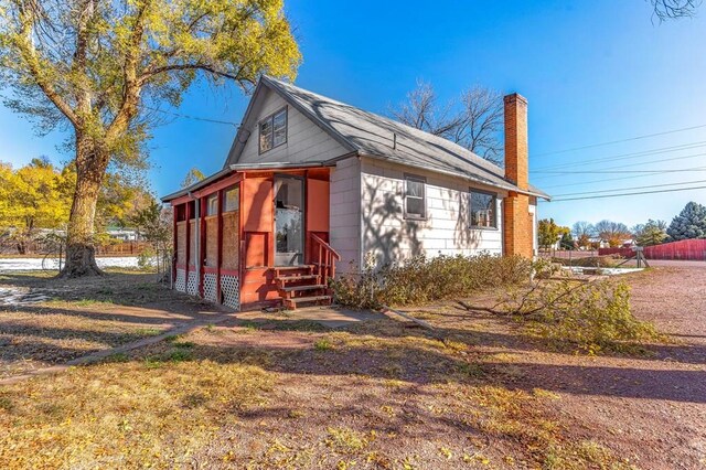 view of property exterior featuring entry steps and a chimney