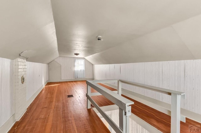 bonus room with light wood-style flooring, visible vents, and vaulted ceiling