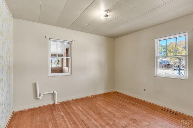 spare room with wood finished floors, visible vents, and baseboards