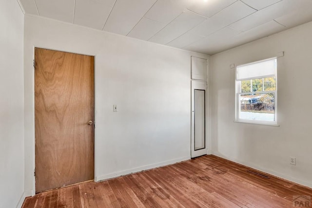 spare room featuring baseboards and wood finished floors