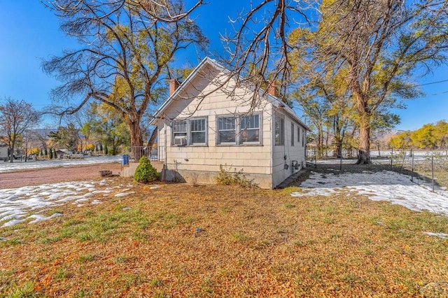 view of property exterior featuring cooling unit, a lawn, and a chimney