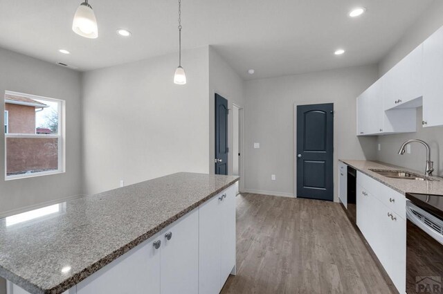280 W Harmony Dr, Pueblo West, CO 81007 - kitchen with white cabinetry, decorative light fixtures, a sink, light stone counters, and light wood finished floors