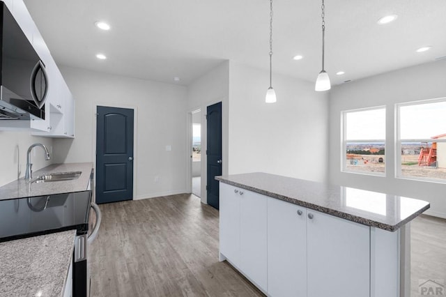 280 W Harmony Dr, Pueblo West, CO 81007 - kitchen featuring light wood finished floors, white cabinetry, a sink, and a kitchen island